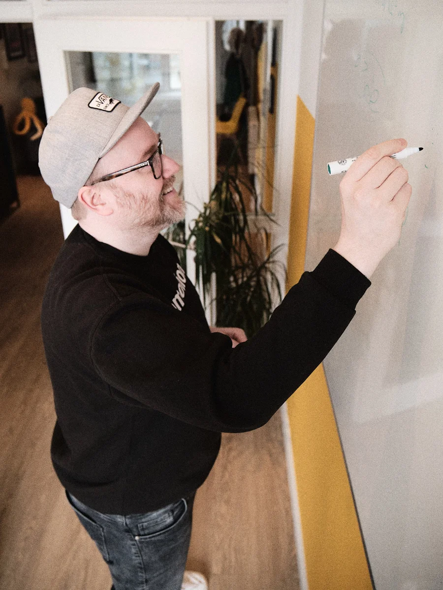 Kreative Projektplanung bei der wemotion Digitalagentur Teammitglied der wemotion Digitalagentur schreibt Ideen und Konzepte an ein Whiteboard während der Projektplanung.