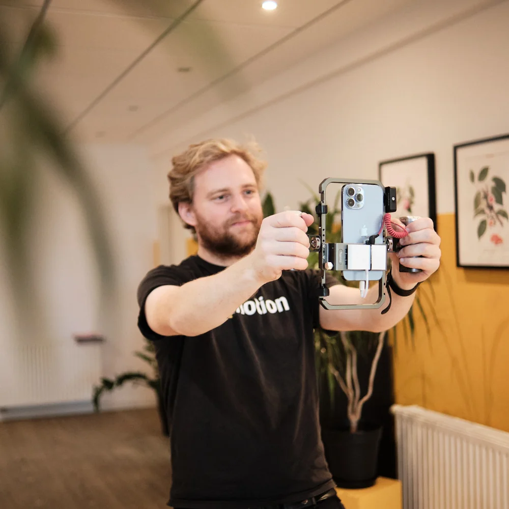 Kreative Content-Erstellung und Videoaufnahmen – wemotion Digitalagentur Mitarbeiter der wemotion Digitalagentur nimmt mit einem Smartphone und Stabilisator ein Video auf – Symbol für kreative Content-Erstellung.